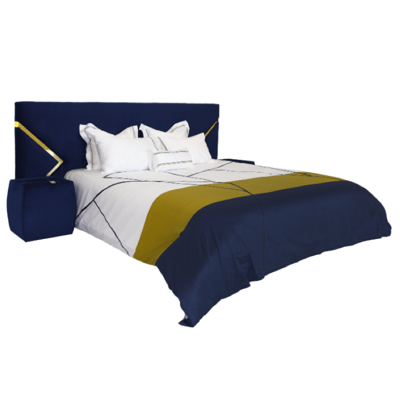 Cama com cabeceira azul-marinho e dourada, mesa de cabeceira azul e edredão geométrico branco, azul e amarelo mostarda.