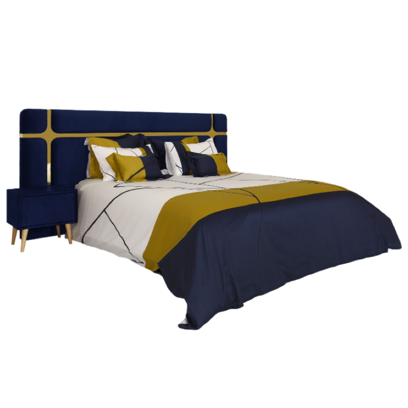 Cama de casal com cabeceira azul-marinho e detalhes dourados, mesa de cabeceira a condizer e roupa de cama geométrica em azul, amarelo e branco.