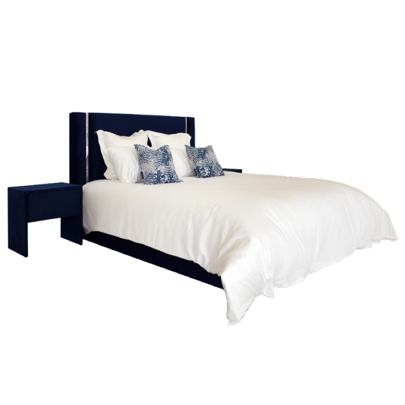 Cama azul-marinho com cabeceira estofada e mesa de cabeceira a condizer. Roupa de cama branca e almofadas azuis estampadas.