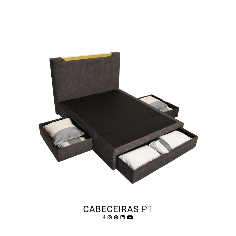 Cama estofada cinzento-escuro com cabeceira dourada e quatro gavetas de arrumação abertas, com almofadas e roupa de cama.